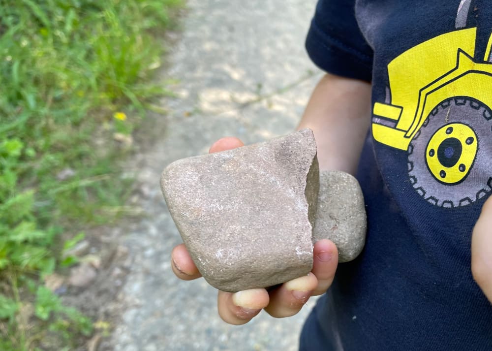 Ein Kind hält zwei schwere Steine in seiner Hand.