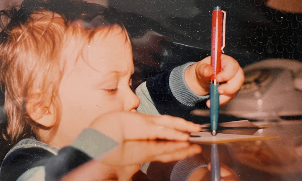 Kleinkind schreibt mit einem Kugelschreiber.